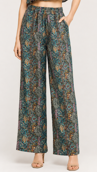 A model is wearing a pair of EVERSHE high-waisted, wide-leg pants with an intricate multicolor paisley and floral pattern in teal, brown, and gold tones, paired with clear high-heeled sandals.